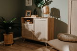 Kommode aus Holz mit zwei Türen und einem offenen Fach, dekoriert mit Büchern, einer Vase und einer Lampe, seitliche Perspektive
