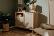 Kommode aus Holz mit zwei Türen und einem offenen Fach, dekoriert mit Büchern, einer Vase und einer Lampe, seitliche Perspektive