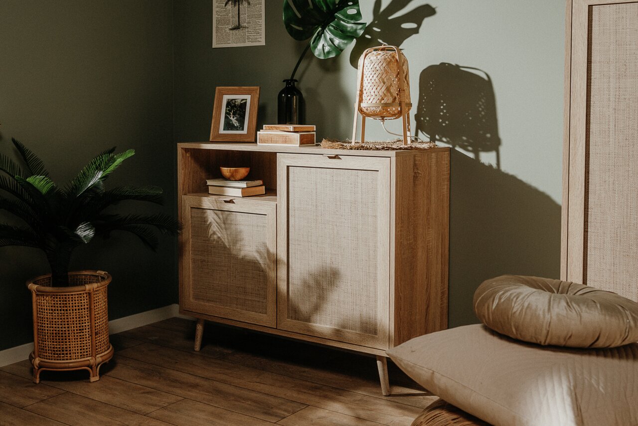 Kommode aus Holz mit zwei Türen und einem offenen Fach, dekoriert mit Büchern, einer Vase und einer Lampe, seitliche Perspektive