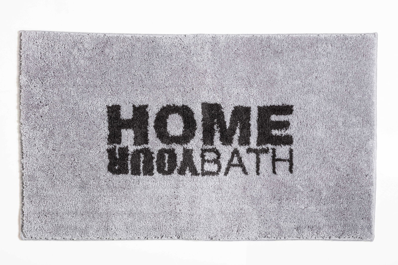 Grauer Badteppich mit schwarzem Schriftzug 'HOME YOUR BATH', von oben betrachtet.