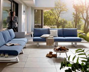 Moderne Outdoor-Lounge mit blauen Sofas und Kissen, umgeben von grüner Natur, aus der Perspektive einer Terrasse.
