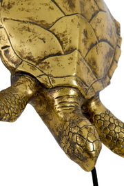 Close-up vanuit schuin bovenaanzicht van een decoratieve goudkleurige schildpad met verweerde afwerking en gedetailleerd schild