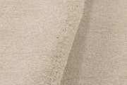 Nahaufnahme eines beigen Uni-Teppichs mit weicher Textur, von der Seite betrachtet.
