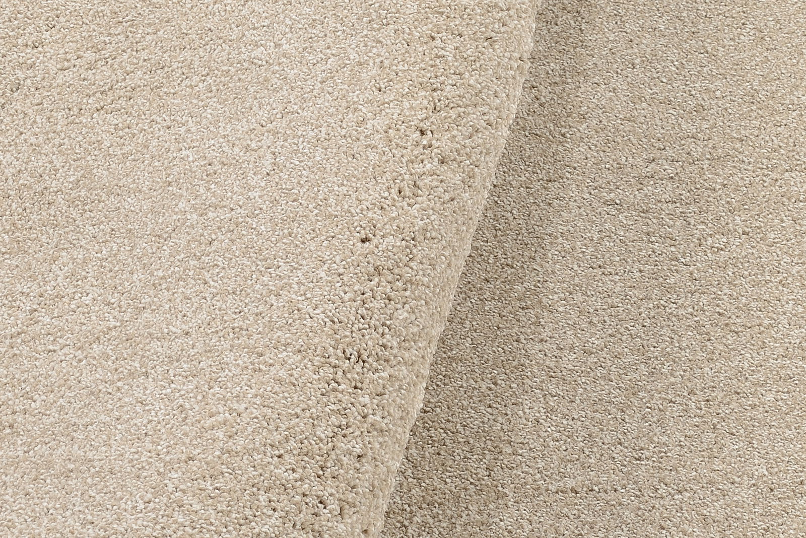 Nahaufnahme eines beigen Uni-Teppichs mit weicher Textur, von der Seite betrachtet.