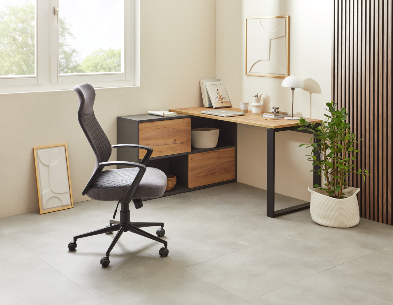 Moderner Winkelschreibtisch in einem hellen Raum, mit einem ergonomischen Bürostuhl und dekorativen Elementen, aus seitlicher Perspektive fotografiert.