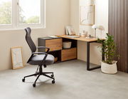 Moderner Winkelschreibtisch in einem hellen Raum, mit einem ergonomischen Bürostuhl und dekorativen Elementen, aus seitlicher Perspektive fotografiert.