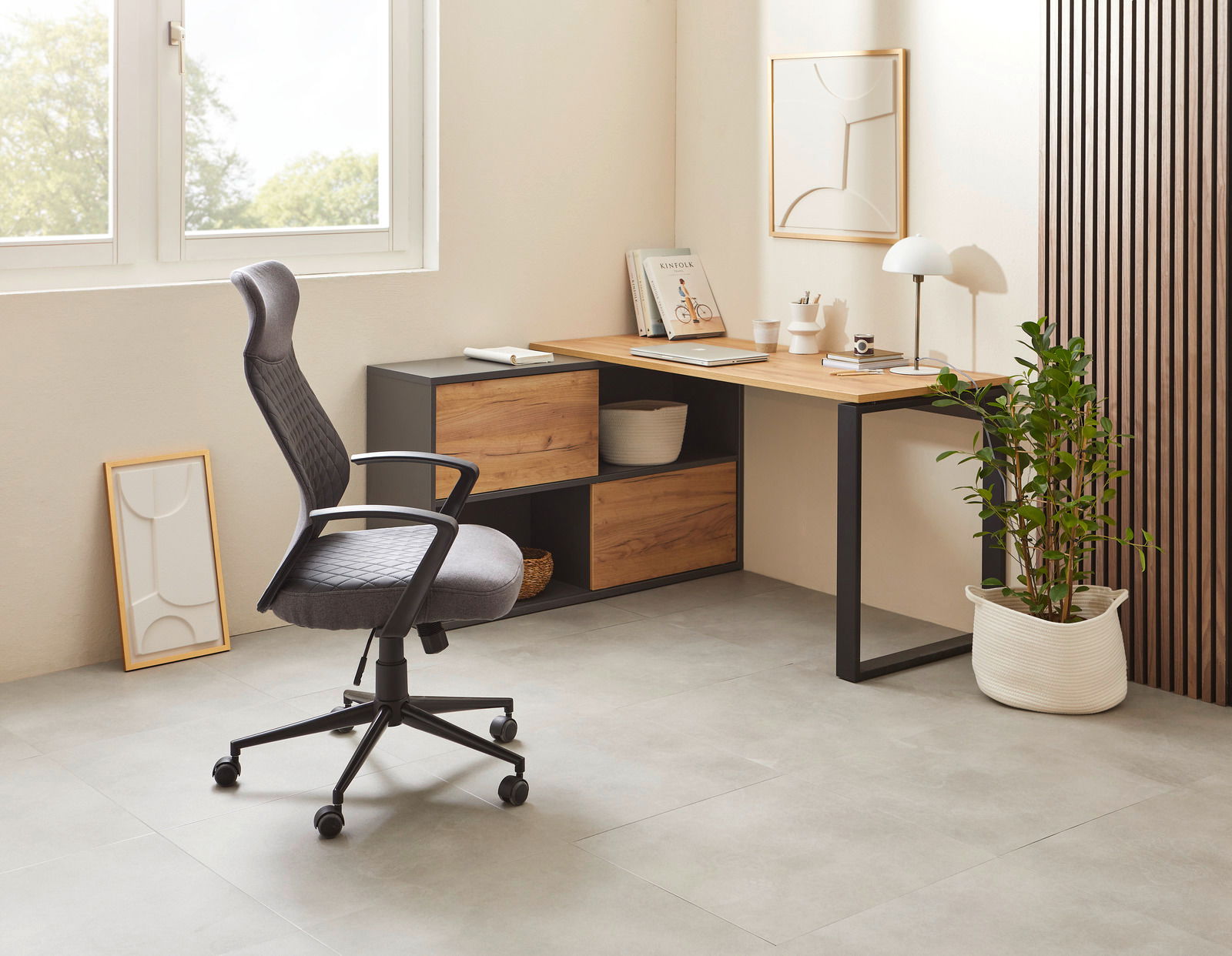 Moderner Winkelschreibtisch in einem hellen Raum, mit einem ergonomischen Bürostuhl und dekorativen Elementen, aus seitlicher Perspektive fotografiert.