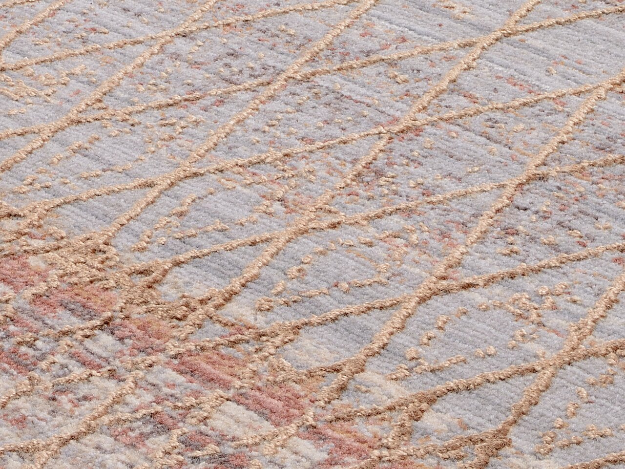 Nahaufnahme eines Designer-Teppichs mit geometrischem Muster in Beige- und Grautönen, diagonale Perspektive.