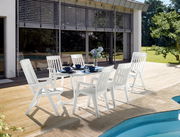 Weißer Gartentisch mit sechs passenden Stühlen auf einer Terrasse, seitliche Perspektive