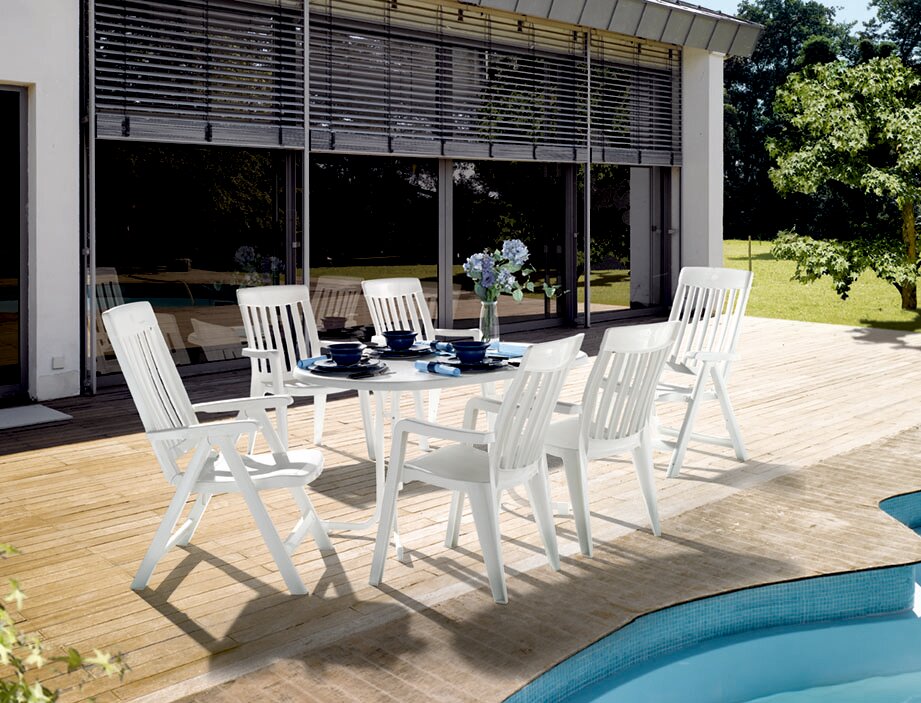 Weißer Gartentisch mit sechs passenden Stühlen auf einer Terrasse, seitliche Perspektive