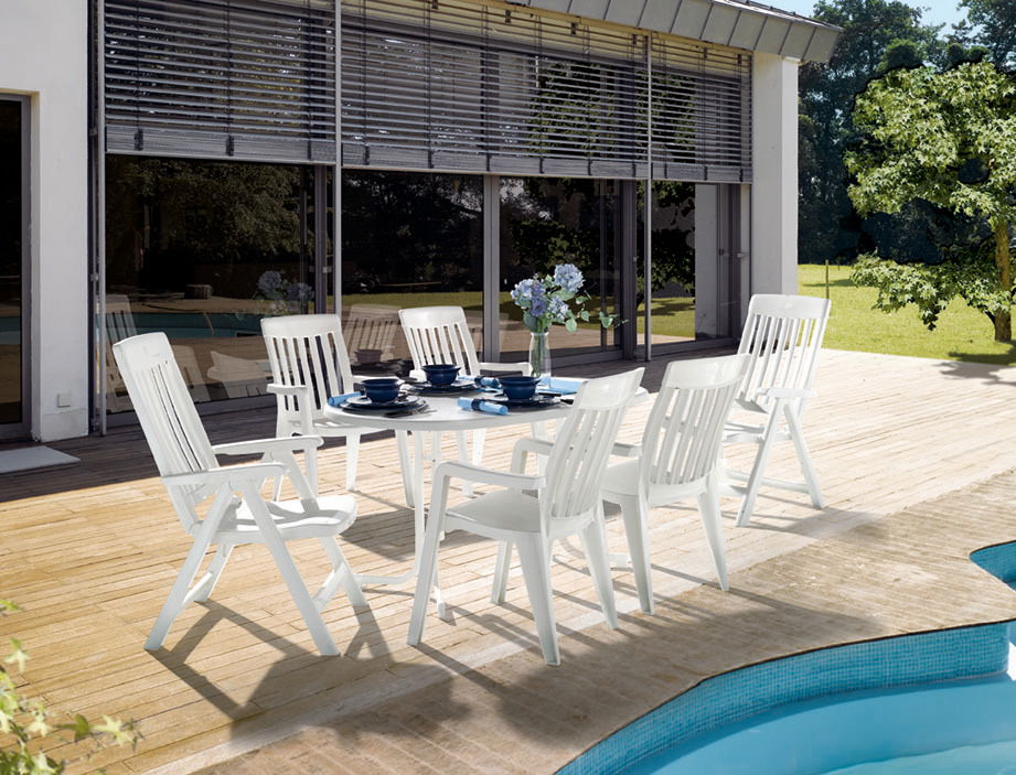 Weißer Gartentisch mit sechs passenden Stühlen auf einer Terrasse, seitliche Perspektive
