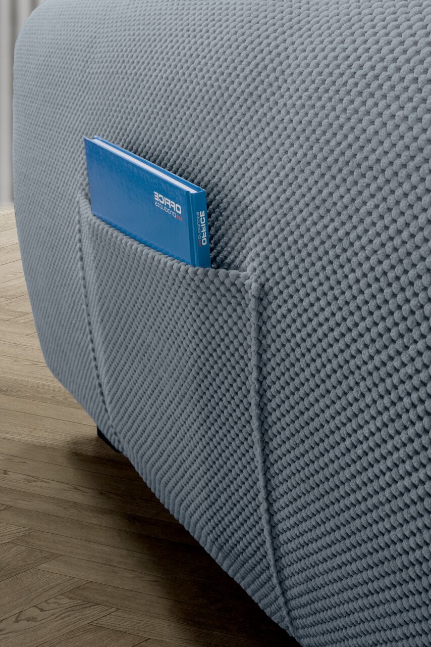 Nahaufnahme einer grauen Rundecke mit strukturierter Oberfläche und einer seitlichen Tasche, in der ein blaues Buch steckt.