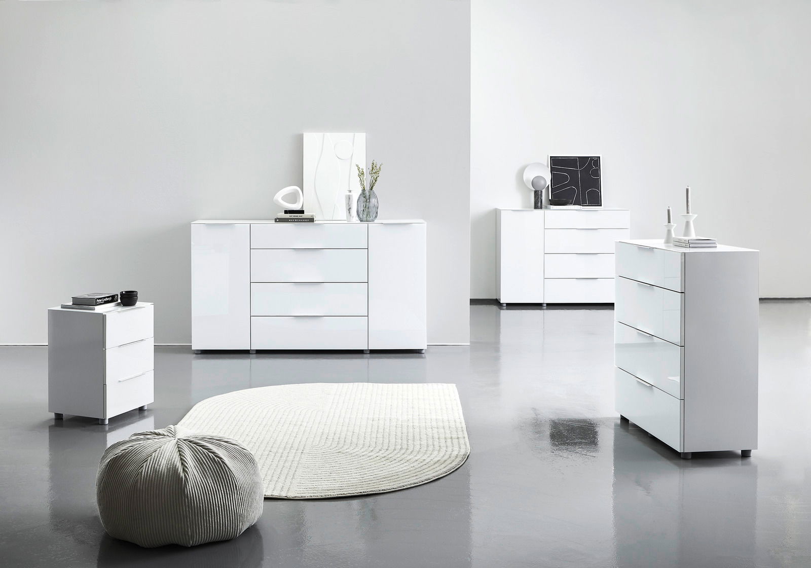 Moderne weiße Hochglanz-Kommoden in einem minimalistischen Raum, fotografiert aus einer seitlichen Perspektive.