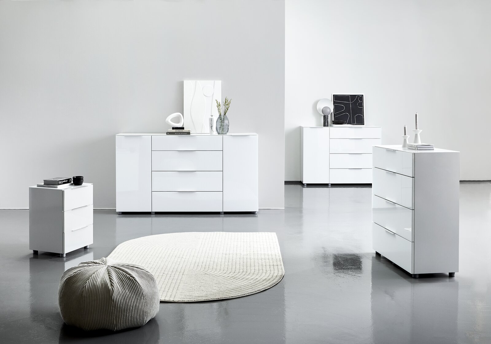 Moderne weiße Hochglanz-Kommoden in einem minimalistischen Raum, fotografiert aus einer seitlichen Perspektive.