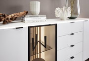Modernes Sideboard mit weißer Oberfläche, dekoriert mit Büchern, einer Vase und einer Skulptur, aus seitlicher Perspektive.