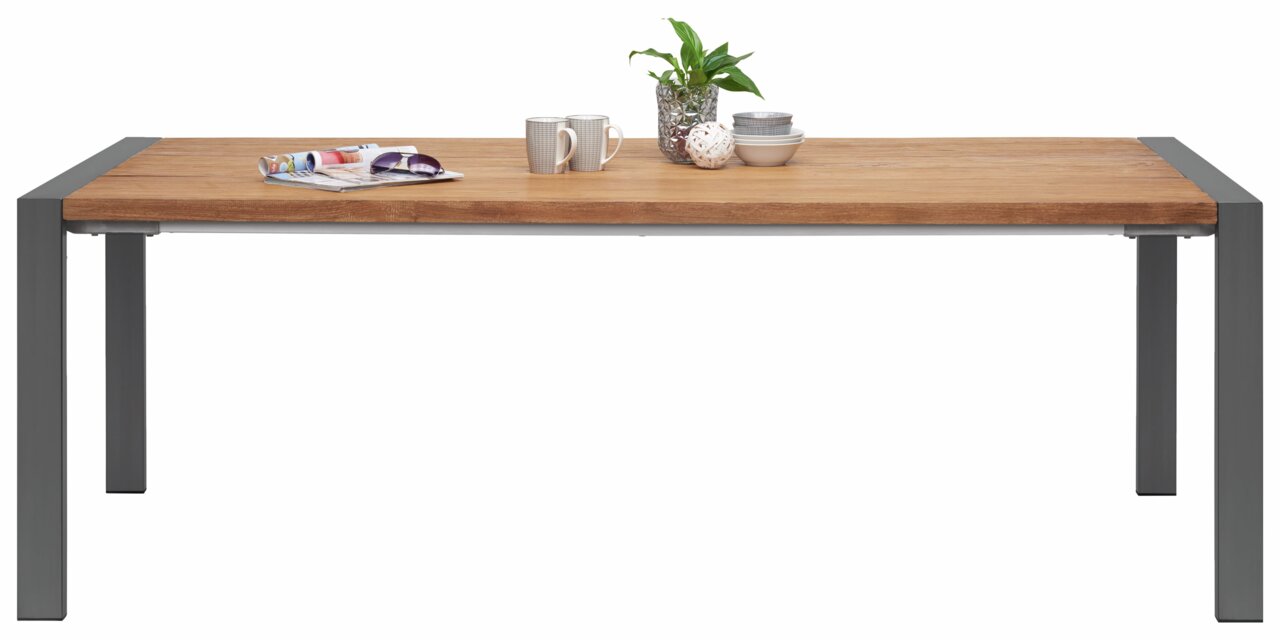 Moderne tuintafel met houten blad en metalen poten, gefotografeerd van voren, versierd met planten en serviesgoed.