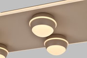 Close-up van een moderne led-plafondlamp met drie ronde lichtelementen, gezien vanaf de zijkant