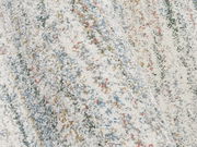 Nahaufnahme eines bunten Frisé-Teppichs mit gemusterten Streifen in verschiedenen Farben, aus seitlicher Perspektive fotografiert.