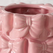 Nahaufnahme einer rosa Vase aus Steinzeug mit Schleifenmuster, seitliche Perspektive