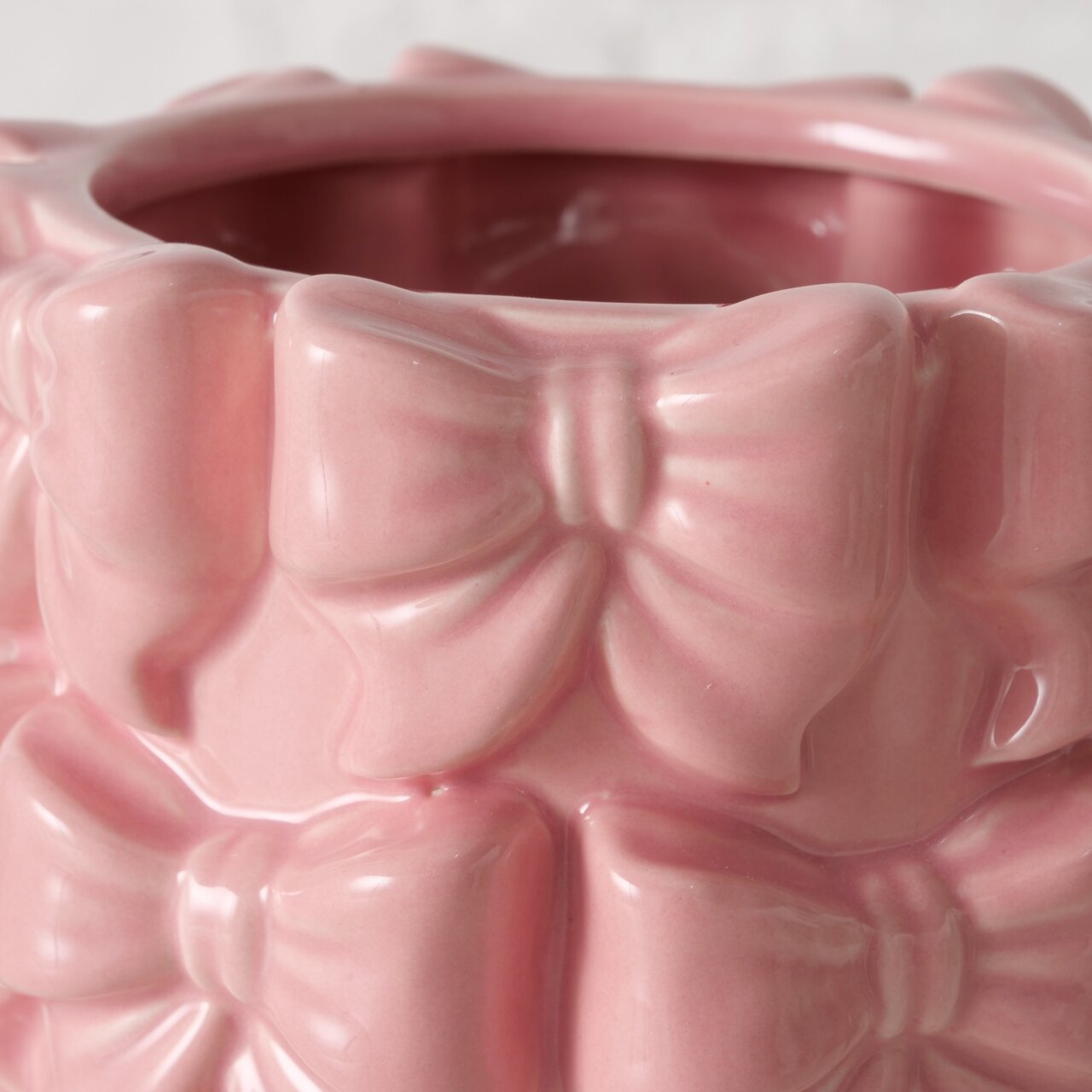 Nahaufnahme einer rosa Vase aus Steinzeug mit Schleifenmuster, seitliche Perspektive