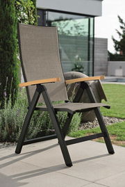 Moderner Klappsessel mit schwarzem Metallrahmen und Holzarmlehnen, auf einer Terrasse im Garten platziert, seitliche Perspektive.