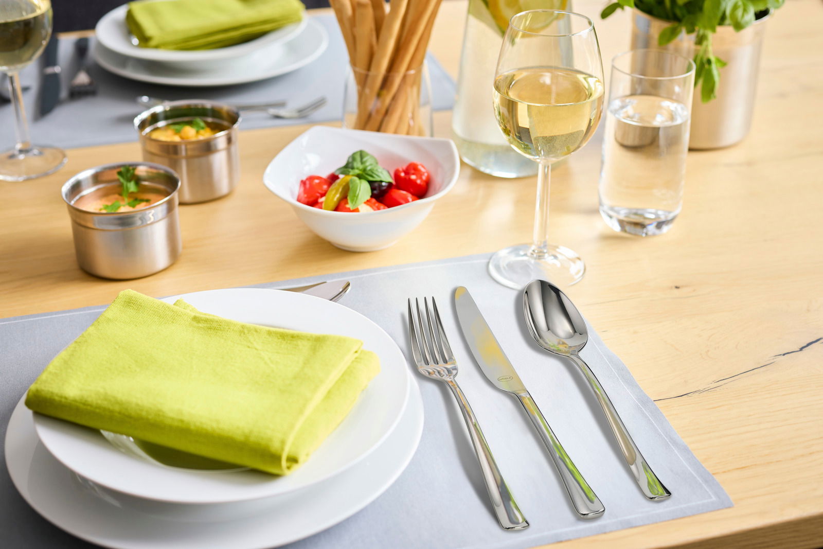 Rösle Besteck-Set 30-tlg. DESIO Elegantes Besteck-Set auf einem gedeckten Tisch mit grünem Stoffserviette, Weinglas und Salat in einer Schale, aus der Vogelperspektive.