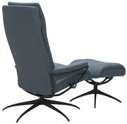 Rückansicht eines modernen blauen Einzelsessels mit passendem Hocker, beide auf schwarzen Drehgestellen.