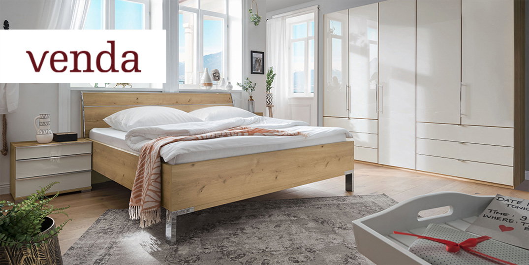 Een lichte slaapkamer met een houten bed, een witte kledingkast en een tapijt op een houten vloer.
