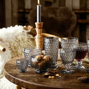 Verschiedene Boston-Gläser auf einem rustikalen Holztisch, seitliche Perspektive, mit Nüssen und einer brennenden Kerze im Hintergrund.