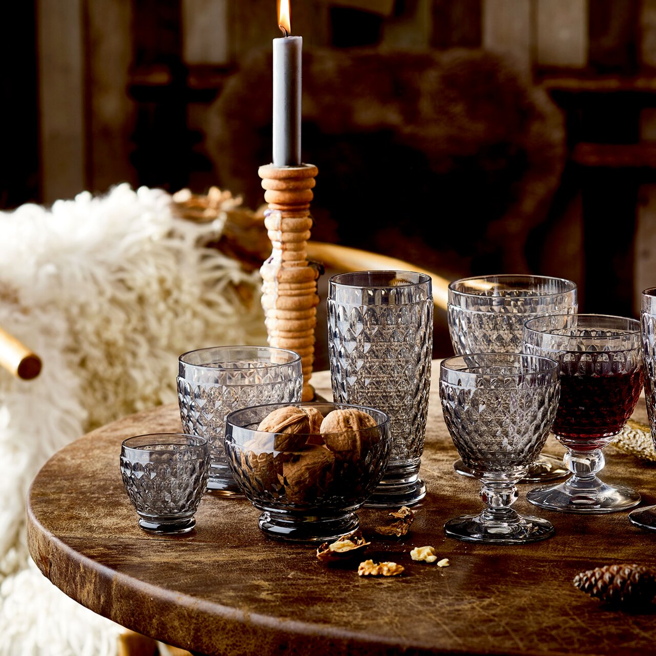 Verschiedene Boston-Gläser auf einem rustikalen Holztisch, seitliche Perspektive, mit Nüssen und einer brennenden Kerze im Hintergrund.