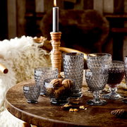 Verschiedene Boston-Gläser auf einem rustikalen Holztisch, seitliche Perspektive, mit Nüssen und einer brennenden Kerze im Hintergrund.