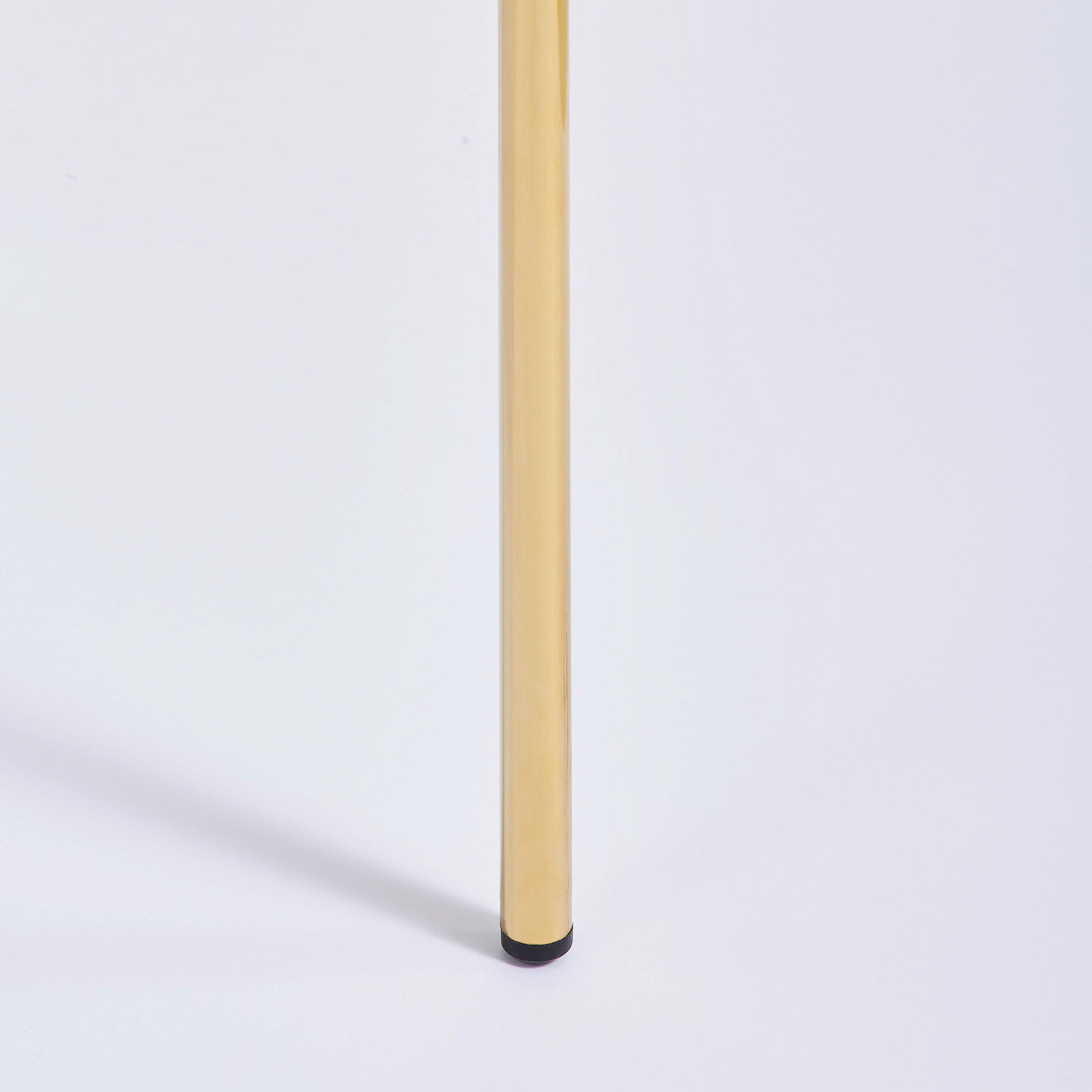 Nahaufnahme eines goldenen Stuhlbeins mit schwarzem Fuß, seitliche Perspektive