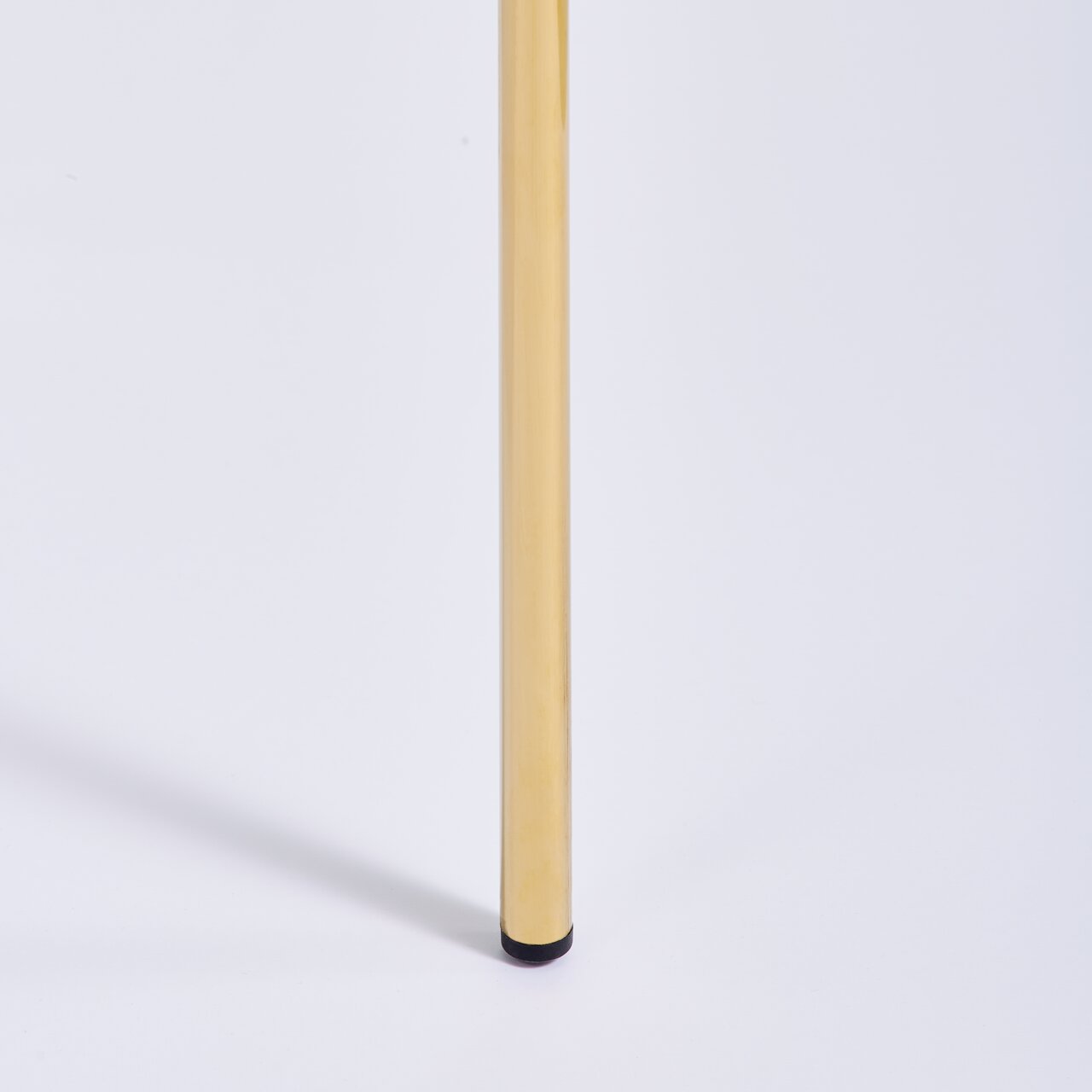 Nahaufnahme eines goldenen Stuhlbeins mit schwarzem Fuß, seitliche Perspektive