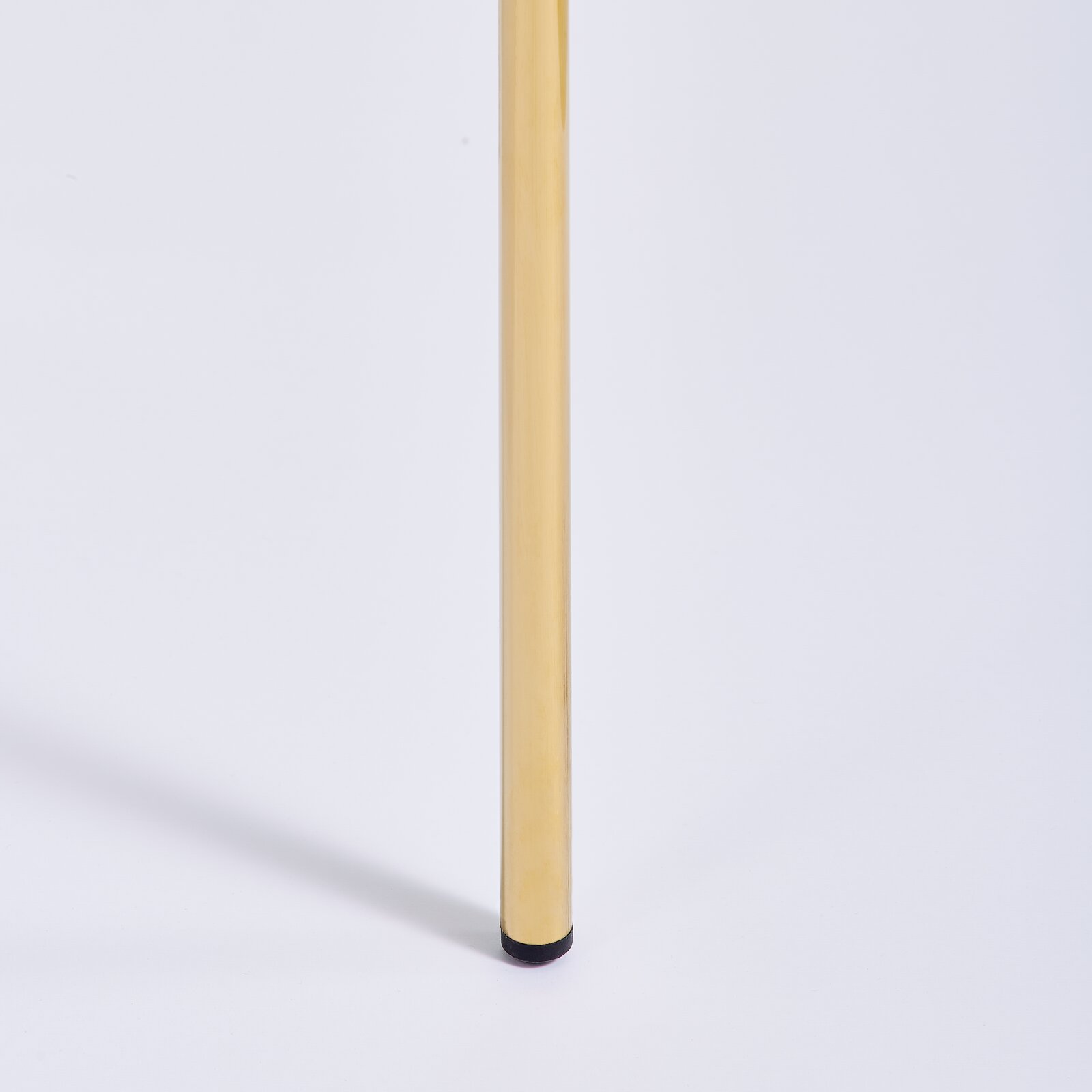 Nahaufnahme eines goldenen Stuhlbeins mit schwarzem Fuß, seitliche Perspektive