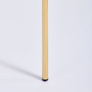 Nahaufnahme eines goldenen Stuhlbeins mit schwarzem Fuß, seitliche Perspektive