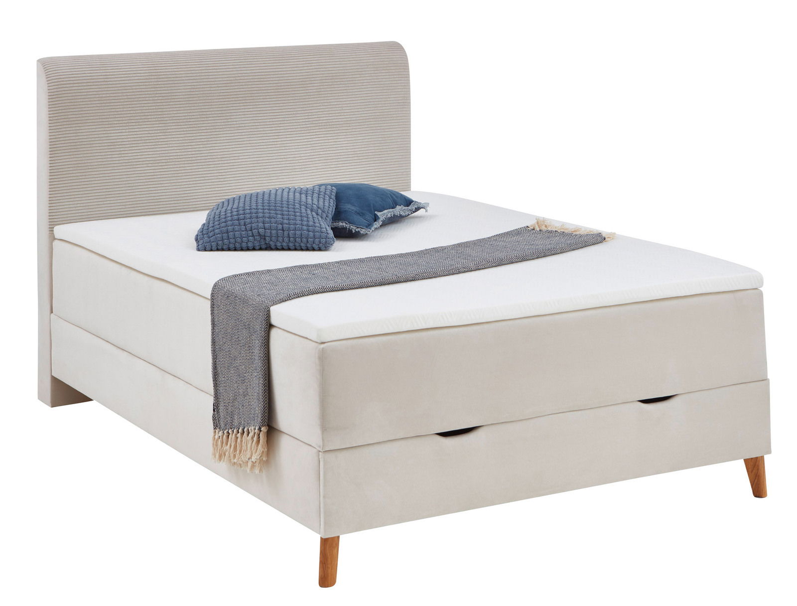 Boxspringbett in seitlicher Perspektive mit beigem Stoffbezug, blauen Kissen und grauer Decke