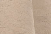 Nahaufnahme eines beigen Fellteppichs mit weicher Textur, seitliche Perspektive