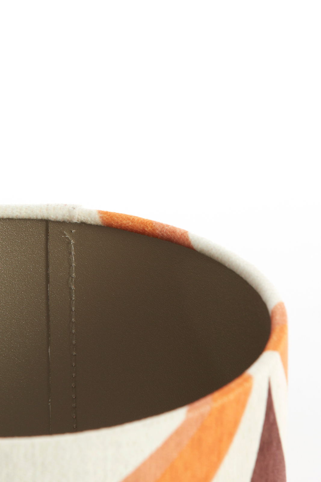 Nahaufnahme eines Lampenschirms mit geometrischem Muster in warmen Farben, von oben betrachtet.