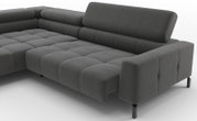 Donkergrijze hoekbank met ribstof bekleding, diepe zitting en verstelbare rugkussens, getoond in schuin vooraanzicht (driekwart) op een witte achtergrond.