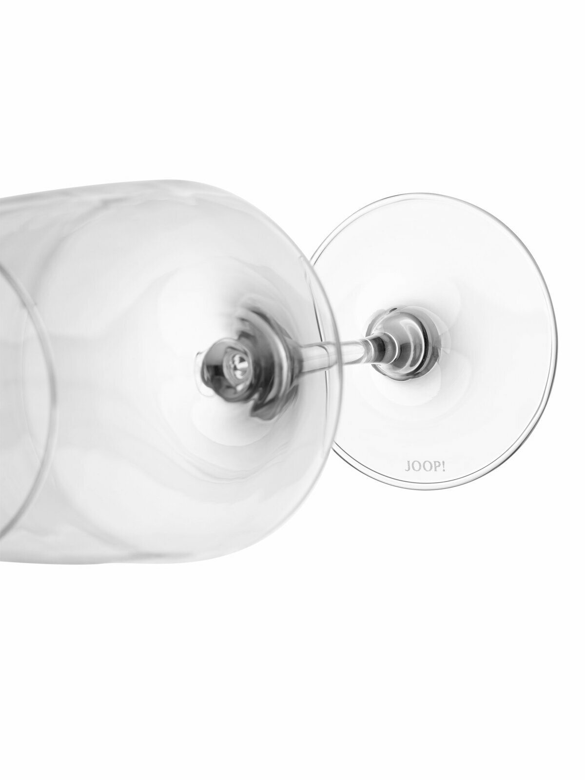 Nahaufnahme eines umgekippten Rotweinglases mit der Aufschrift 'JOOP!' auf dem Fuß, seitliche Perspektive.