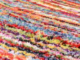 Bunte, flauschige Teppichoberfläche in Nahaufnahme, perspektivisch schräg von der Seite fotografiert.