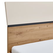 Nahaufnahme eines Bettes mit einem Kopfteil aus Holzoptik und einer cremefarbenen oberen Platte, seitliche Perspektive.