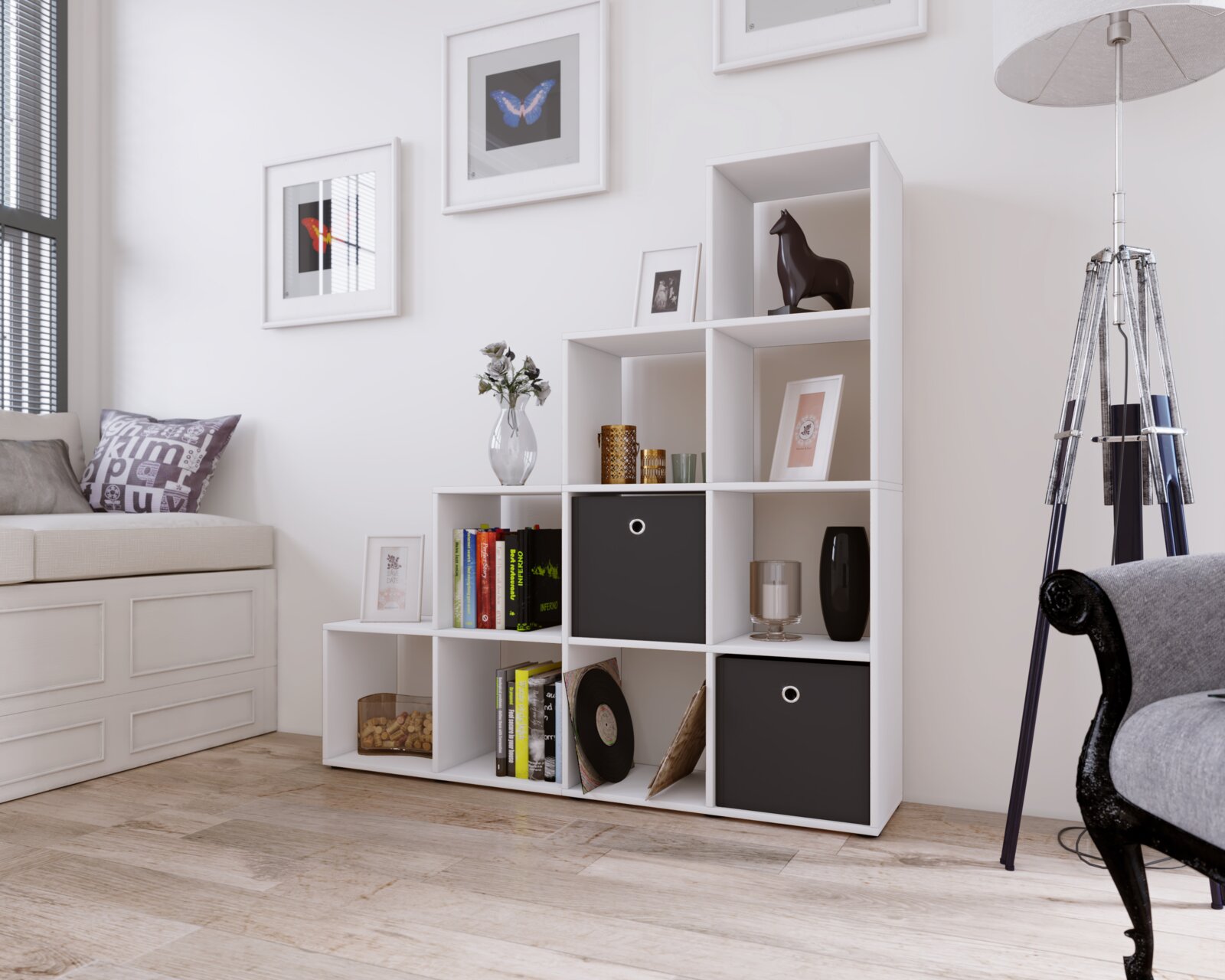 Weißes, modulares Würfelregal mit offenen Fächern und zwei schwarzen Stoffboxen im hellen Wohnzimmer, schräg von vorn aus leicht erhöhter Perspektive aufgenommen.