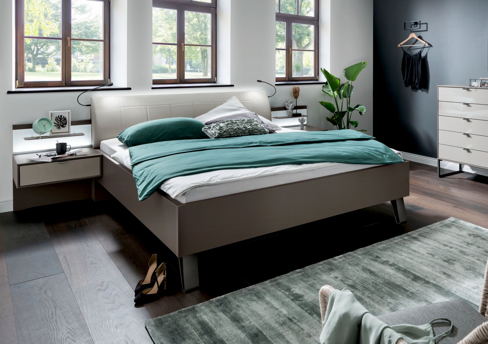 Modernes Futonbett in einem stilvollen Schlafzimmer, seitliche Perspektive mit grüner Bettwäsche und eleganten Nachttischen.