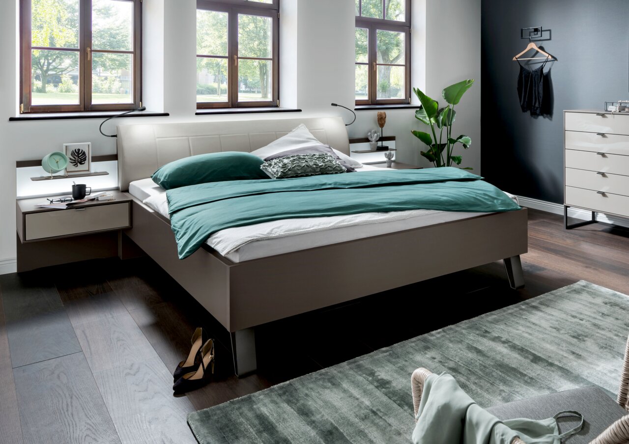 Modernes Futonbett in einem stilvollen Schlafzimmer, seitliche Perspektive mit grüner Bettwäsche und eleganten Nachttischen.