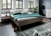 Modernes Futonbett in einem stilvollen Schlafzimmer, seitliche Perspektive mit grüner Bettwäsche und eleganten Nachttischen.