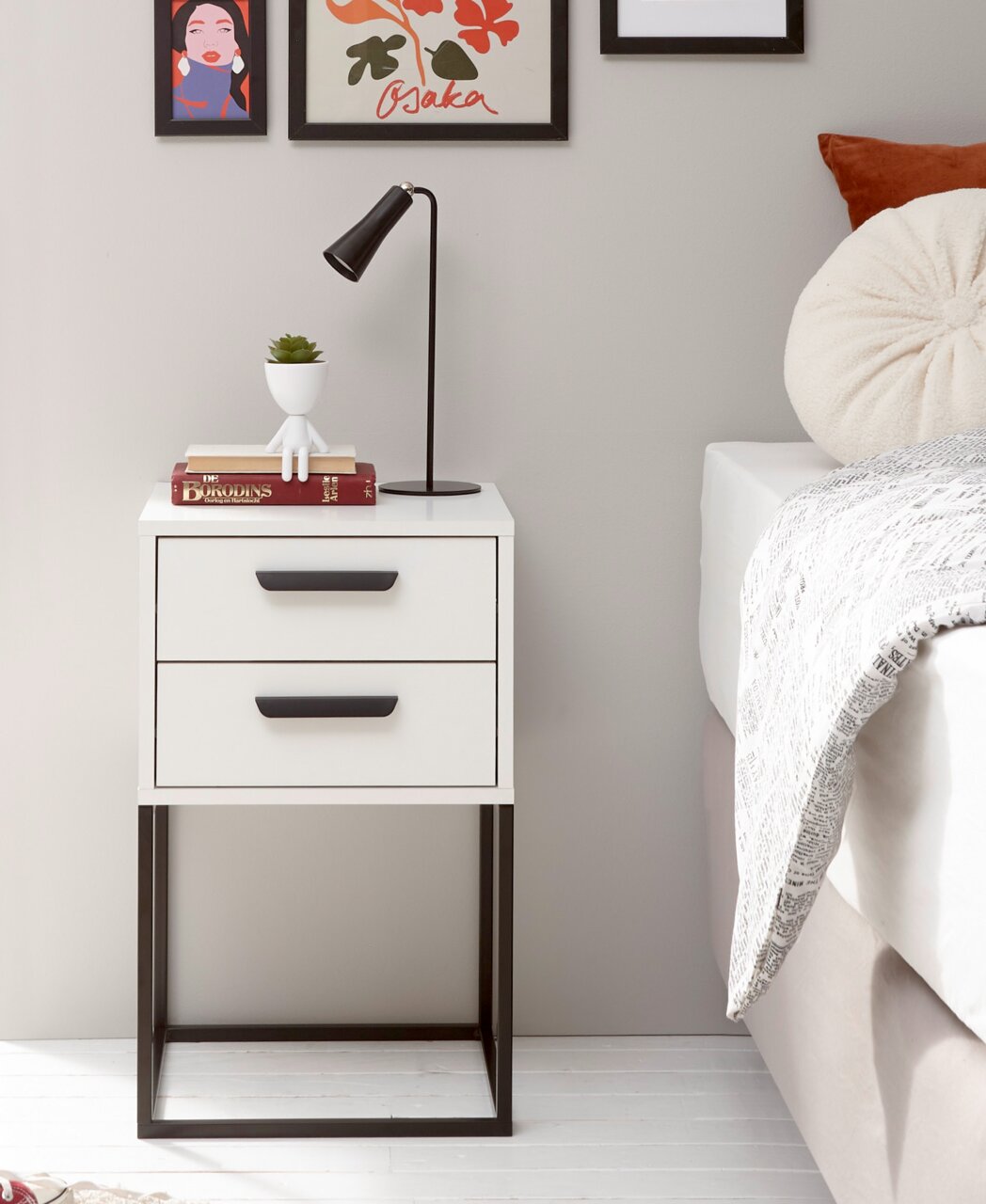 Moderne Nachtkommode mit zwei Schubladen, schwarzem Metallgestell und Dekoration, seitliche Perspektive