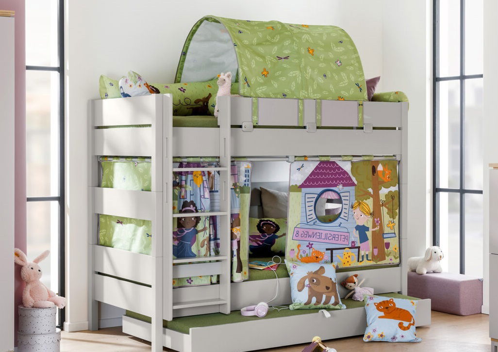 Hochbett mit grünem Baldachin und bunten Vorhängen, dekoriert mit Partykissen, darunter ein Kissen mit Hundemotiv, aus der Perspektive von vorne links.