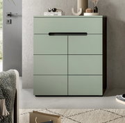 Modernes mintgrünes Sideboard/Kommode mit glatten Fronten und integrierter schwarzer Griffleiste, dekoriert mit Büchern und Vasen, in einem Wohnraum – Frontalansicht leicht von links.