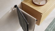Zwarte handdoekhouder van tesa MOON BLACK, aan de muur bevestigd, met twee handdoeken, gefotografeerd vanuit vogelperspectief.